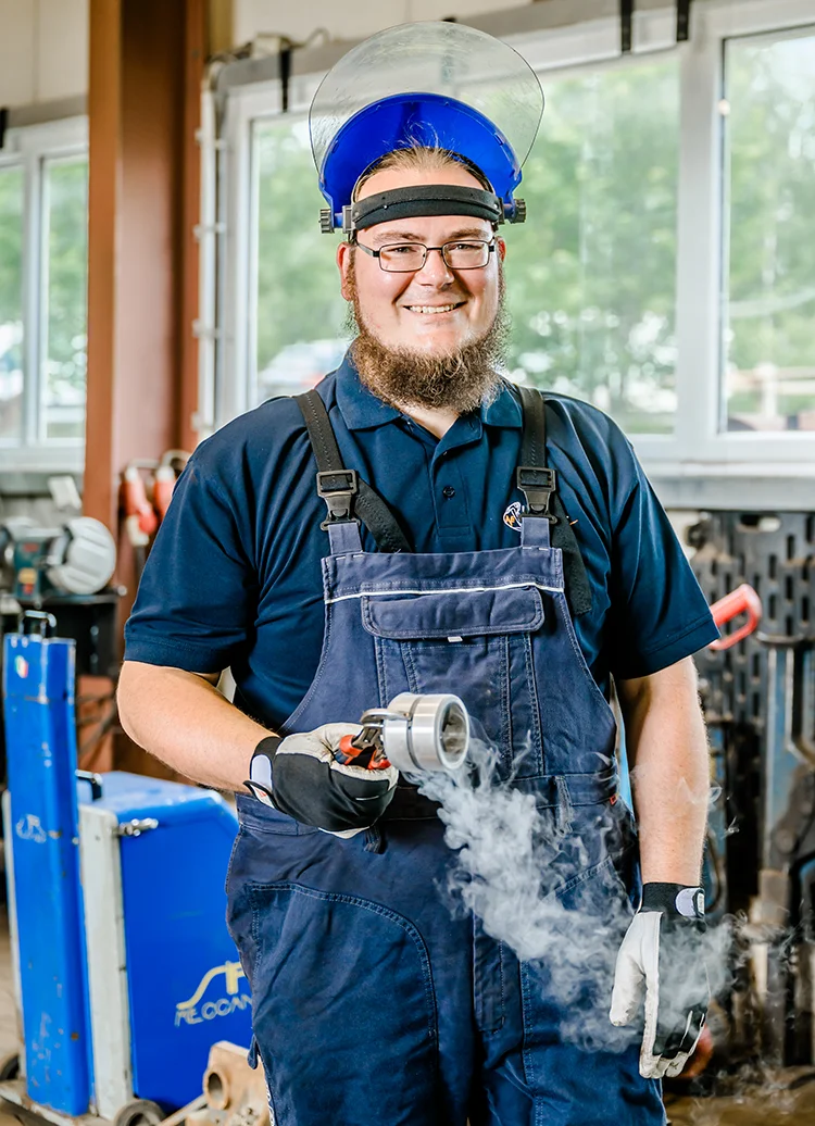 Ein freundlicher und kompetenter Mitarbeiter der Firma AVE Krämer zeigt ein gefertigtes Bauteil aus der Produktionsstätte in Mayen.